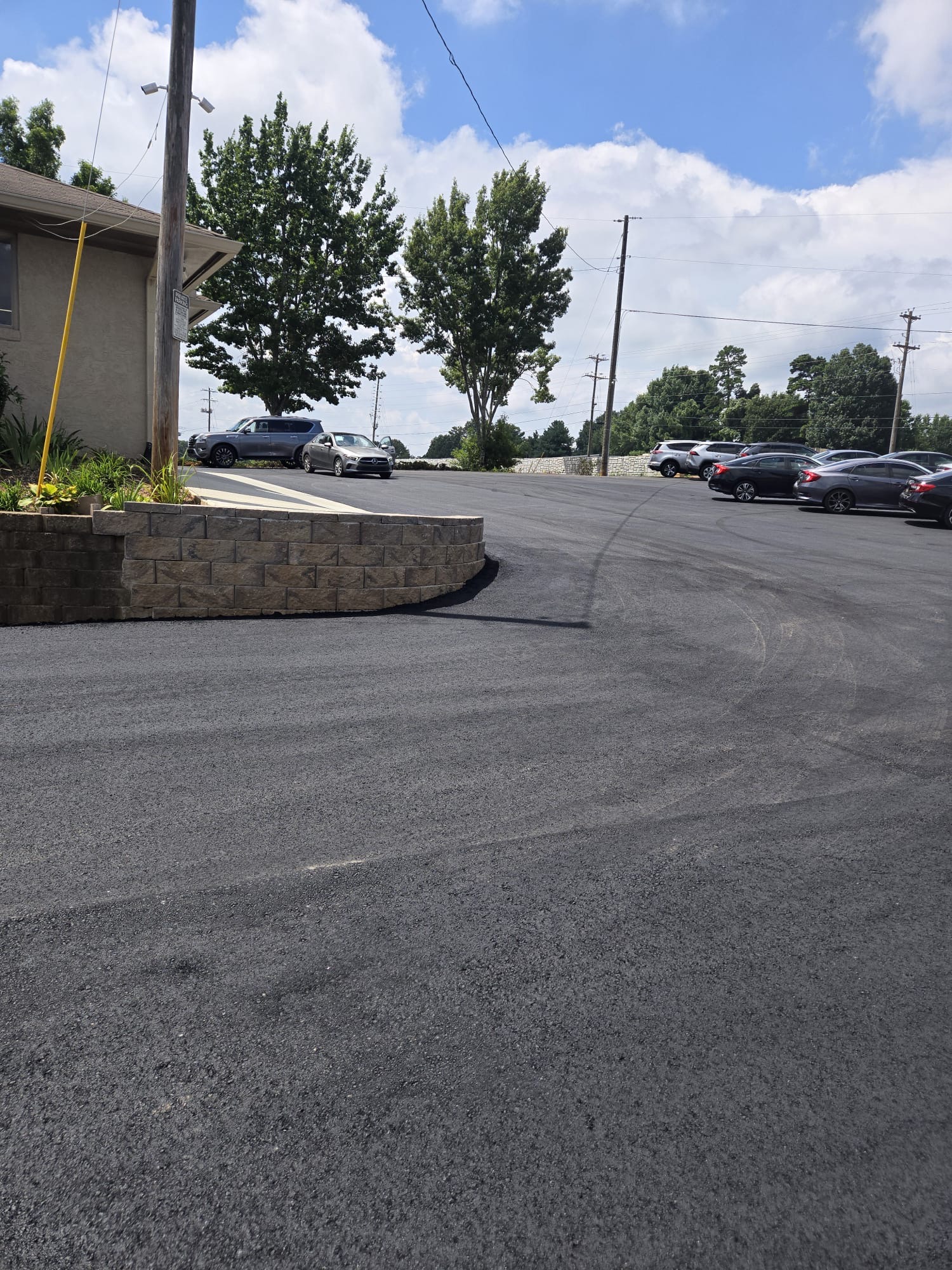 Stone retaining wall bordering a freshly paved parking lot