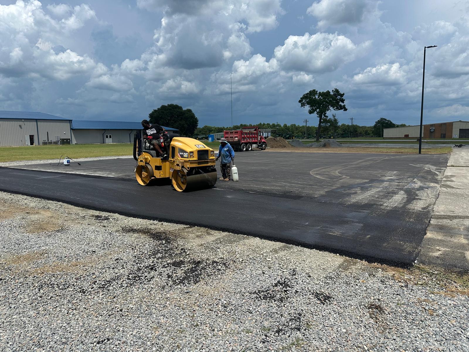 Norka Contracting crew compacting a freshly paved lot under a bright blue Georgia sky